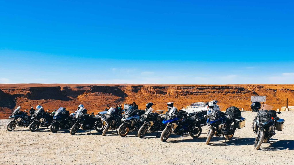 Motorradtouren & Motorradtransporte für unvergessliche Abenteuer. Motorräder in einer Reihe mit einer schluchtartigen Landschaft im Hintergrund bei einem Kaffeestopp auf unserer Marokko-Motorradtour.