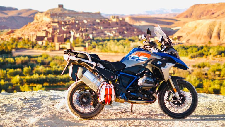 BMW 1250GS vor der historischen Kulisse der alten Stadt Aït-Ben-Haddou unter der strahlenden Sonne während unserer Marokko-Motorradtour
