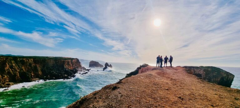 Gruppe von Motorradfahrern unterhält sich vor einer atemberaubenden Kulisse des Atlantischen Ozeans in der Nähe von Cabo Sao Vicente auf unserer Motorradtour durch Südportugal & Andalusien.