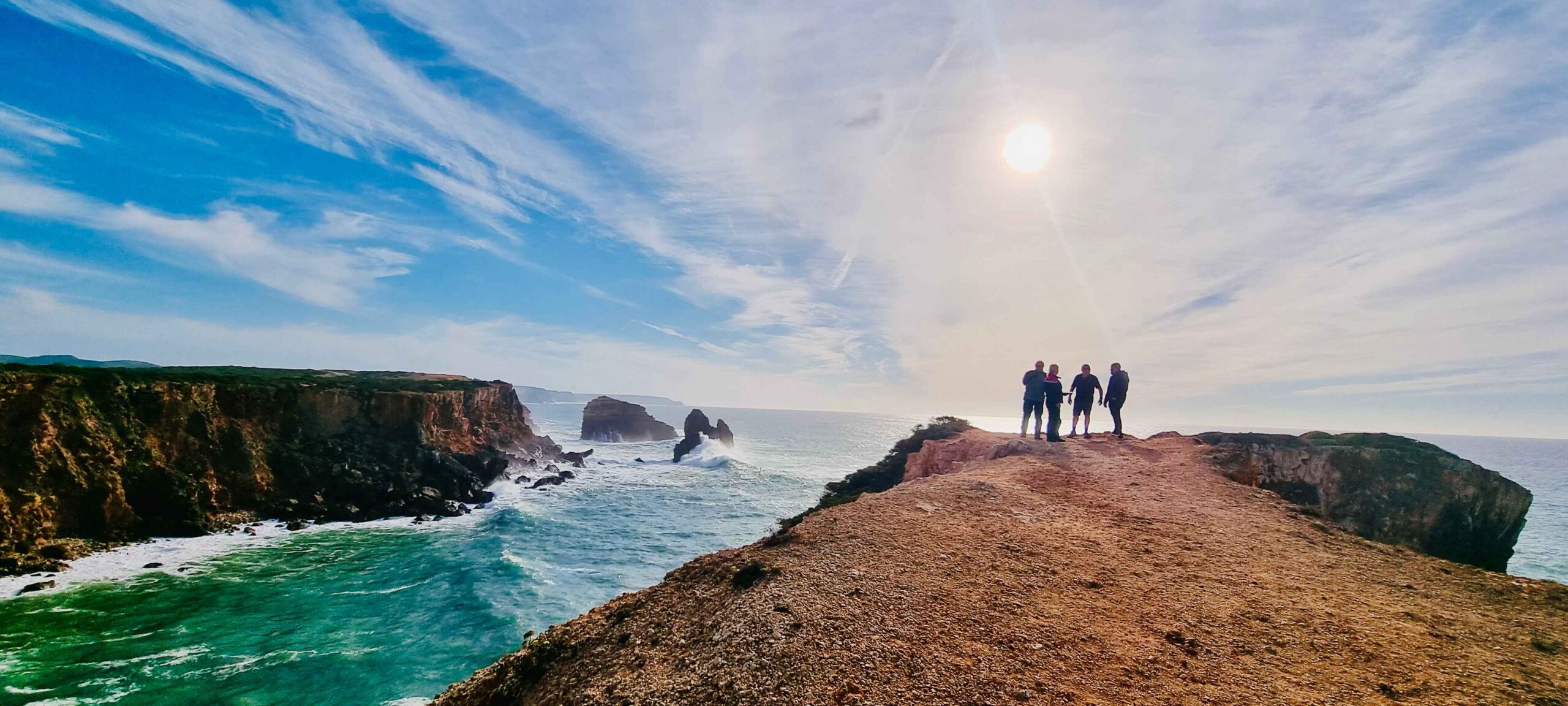 Gruppe von Motorradfahrern unterhält sich vor einer atemberaubenden Kulisse des Atlantischen Ozeans in der Nähe von Cabo Sao Vicente auf unserer Motorradtour durch Südportugal & Andalusien.